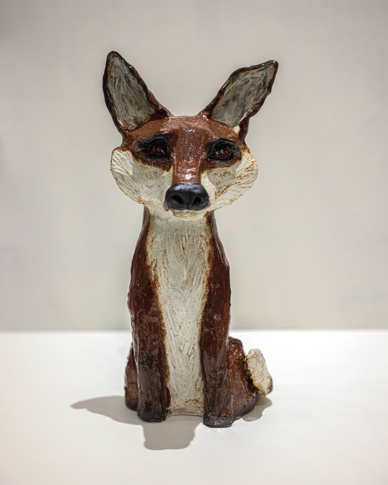 Seated ceramic fox sculpture in russet and cream glazes